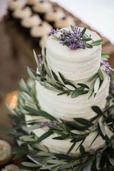 a wedding cake with purple flowers and greenery