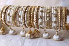 a bunch of bracelets are lined up on a white tablecloth with gold accents