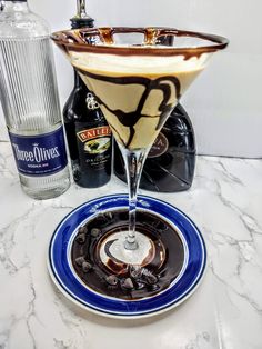 a drink in a martini glass on a plate next to an empty bottle and glasses