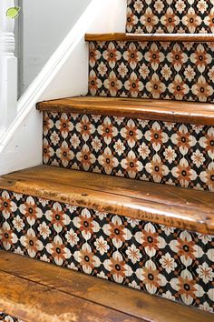 the stairs are decorated with orange and white flowers on black tiles, along with wooden handrails