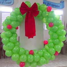 a wreath made out of green balloons with a red bow on the front and side