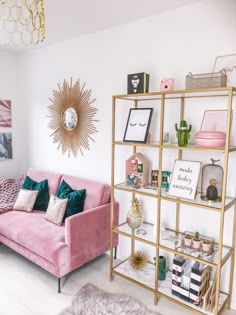 a living room with pink couches and gold shelving units on the wall above them