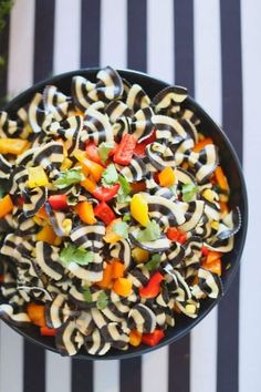 a bowl filled with pasta and vegetables on top of a striped table cloth