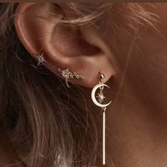 a close up of a person's ear with stars and moon dangling from it