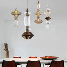 a dining room table with chairs and lights hanging from the ceiling