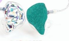 a pair of ear buds with green glitter on them and a diamond in the middle