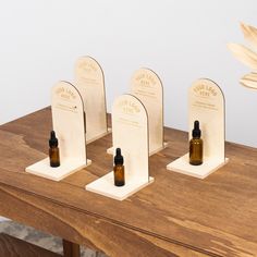 three bottles of essential oils sit on wooden stands with leaves in front of them and one is empty