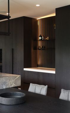 a dining room table and chairs in front of a black wall with shelves on it