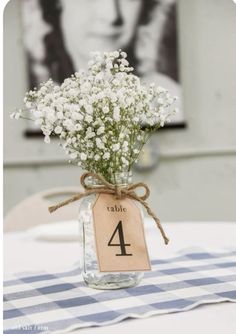 a mason jar filled with baby's breath sitting on top of a checkered table cloth