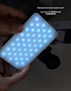 a person holding a cell phone in their hand with blue lights on the back of it