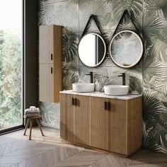 a bathroom with two sinks, mirrors and palm leaves on the wall next to it