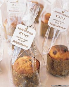 some muffins wrapped in plastic and sitting on a table with tags attached to them