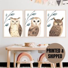 three owls sitting on top of a table in front of a wall mounted art piece