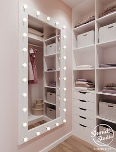 a walk in closet with lots of white drawers and lights on the wall above it