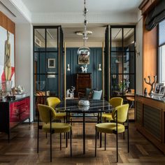 a dining room table with yellow chairs and a glass top in front of a window