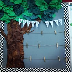 a tree made out of paper with clothes pins attached to it and some green leaves hanging from the branches