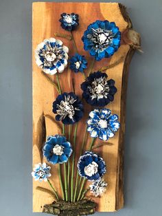 blue and white flowers are arranged on a wooden plaque with a bird perched on it