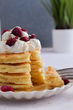 a stack of pancakes topped with whipped cream and raspberries