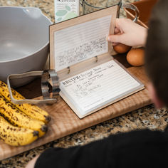 a person writing on a clipboard next to some bananas and an egg carton