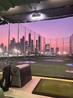 an indoor golf course with city lights in the background