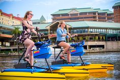 two women riding on paddle boats in the water