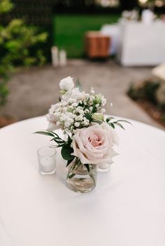 a vase filled with flowers sitting on top of a table next to two shot glasses