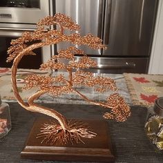 a copper tree sculpture sitting on top of a table next to some jars and spoons