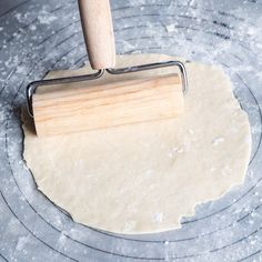 a rolling pin on top of dough in the middle of a circular pan with flour