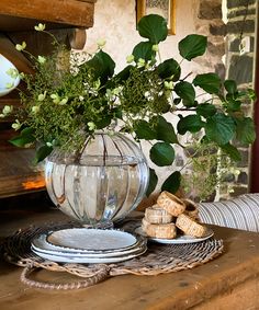 a vase filled with flowers sitting on top of a wooden table next to plates and wine corks