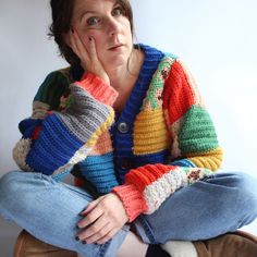 a woman sitting on the floor with her hand under her chin and looking at the camera