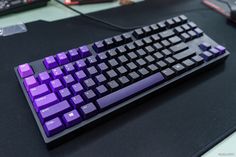 a purple and black keyboard sitting on top of a desk