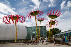 people are walking around in front of some large sculptures that look like flowers and plants