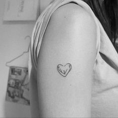 a small heart tattoo on the left upper half of the arm, which is drawn in black and white