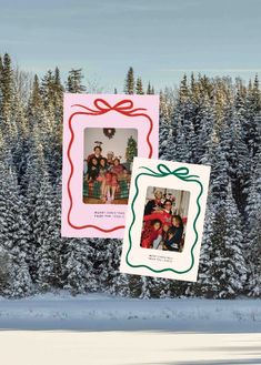 two christmas cards hanging from the side of a snowy tree covered field with evergreens