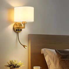 a lamp that is on the side of a wall next to a bed with pillows