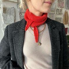 a woman wearing a red scarf standing in front of a wall