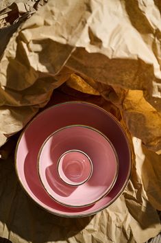 an empty pink bowl sitting on top of a piece of brown paper next to a knife and fork