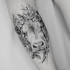 a cow with flowers on its head is shown in this black and white tattoo design