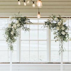 the wedding arch was decorated with greenery and white flowers, along with hanging lights