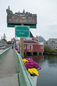 a welcome sign to kennebunkport along the water with flowers in front