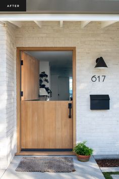 the front door of a house with a potted plant on the doorstep and mailbox in the background