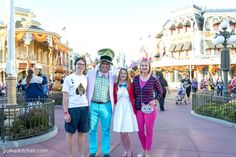 three people posing for a photo in front of mickey mouse's castle