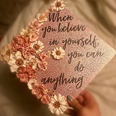 someone holding up a pink graduation cap with flowers on it that says when you believe in yourself, you can do anything