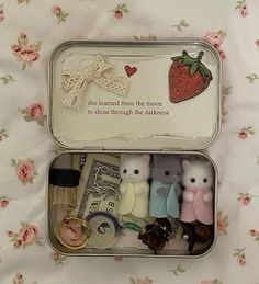 two tins filled with tiny stuffed animals sitting on top of a bed next to each other