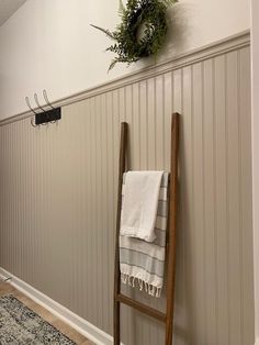 a towel rack is hanging on the wall next to a ladder with a wreath above it