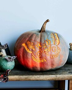 two pumpkins sitting on top of a wooden shelf next to each other with designs painted on them