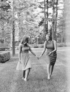 two women are holding hands and walking in the grass