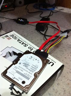 a hard drive sitting on top of a white box with wires attached to it's sides