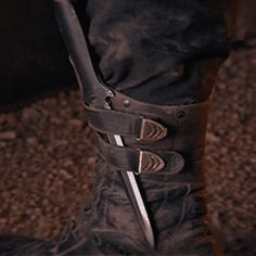 a person wearing black boots and holding a knife