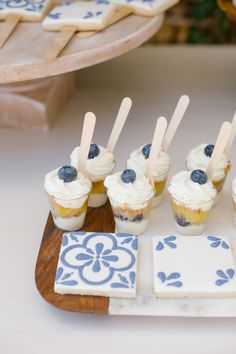 small cupcakes with blueberries are on a wooden tray next to some cookies